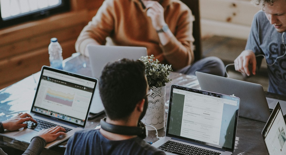 People in a meeting using laptops around a table